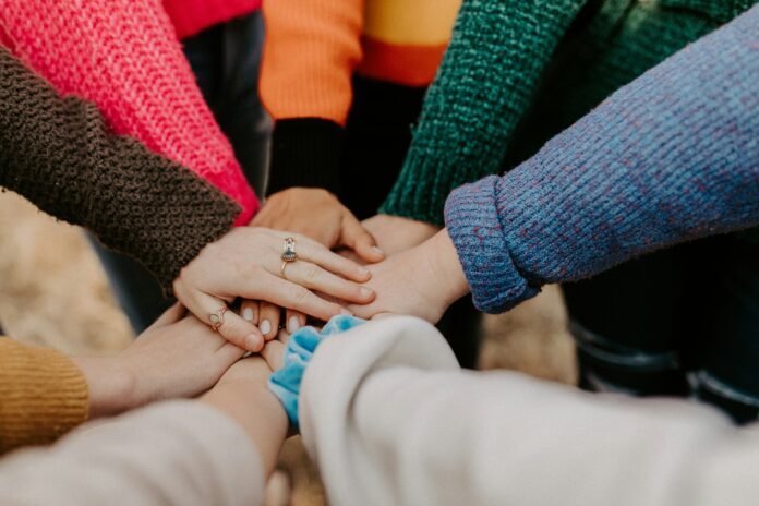 A group of people holding hands together to represent Grants for Good Fund