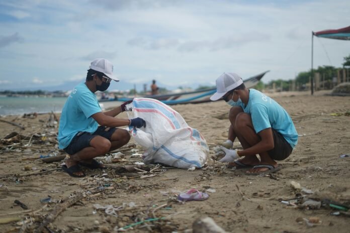 Two men picking dirt's from the beach to represent Growing Roots Grant