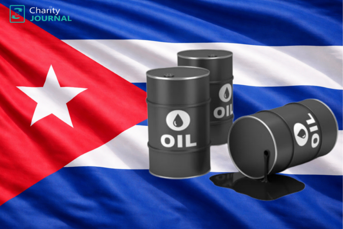 Cuban flag as a backdrop with three black oil barrels on the foreground