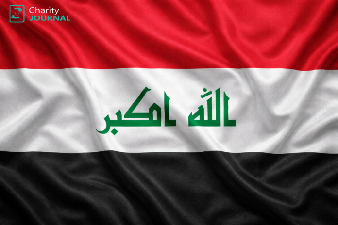 A rippling Iraqi flag with a green arabic text in the center.