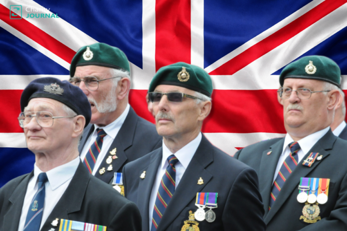 British veterans wearing formal suits stand in front of a large flag